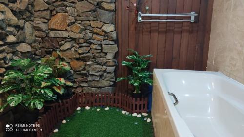 a bathroom with a bath tub and a stone wall at Villa Dalam laut 530 in Pantai Cenang