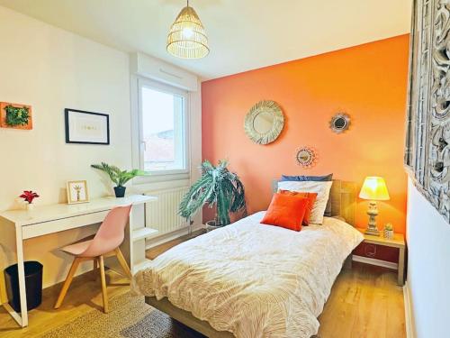- une chambre avec un mur orange, un lit et un bureau dans l'établissement LOASIS - Appart T4 proche Gare et Centre Ville, à Villefranche-sur-Saône