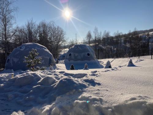 two igloo domes in the snow with the sun in the background at Poziom 713 in Trzebunia