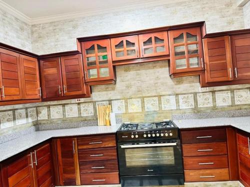 a kitchen with wooden cabinets and a stove top oven at Oceans-Opulence/3BR-5 BEDS in Dar es Salaam