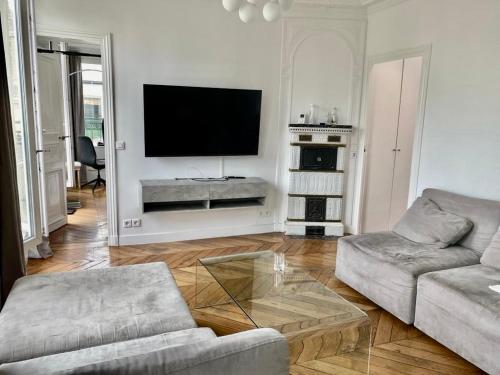 sala de estar con sofá y TV de pantalla plana en Bel appartement Montparnasse 70m2 en París
