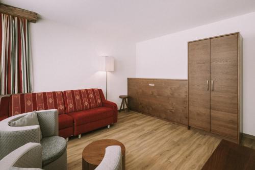 a living room with a red couch and a cabinet at Hotel Montana in Obertauern