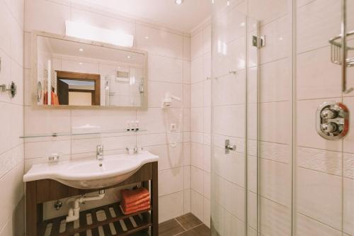 a white bathroom with a sink and a shower at Hotel Montana in Obertauern