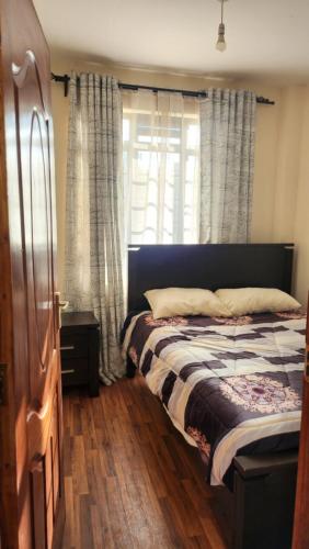 sypialnia z łóżkiem i oknem z zasłonami w obiekcie Delight Stays w mieście Thika