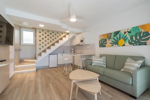 ein Wohnzimmer mit einem Sofa, einer Küche und einer Treppe in der Unterkunft Bungalows Cordial Green Golf in Maspalomas