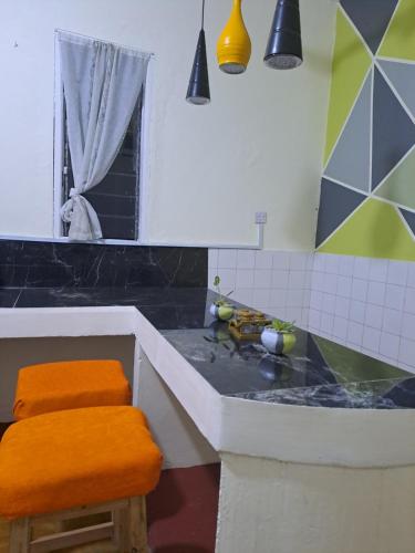 モンバサにあるZahra Homesのバスルーム(バスタブ、オレンジのスツール付きのシンク付)