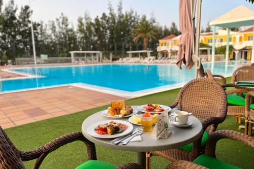 a table with food on it next to a pool at Bungalows Cordial Green Golf in Maspalomas