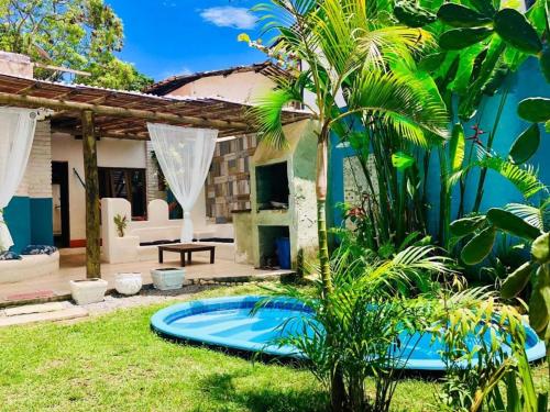 un patio trasero con una piscina azul en el césped en Aldeia dos Encantos Inn en Arraial d'Ajuda