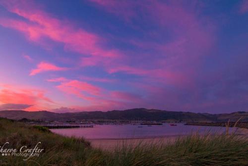 a sunset over a body of water with pink clouds at Bass Retreat - Dog Friendly in Skenes Creek