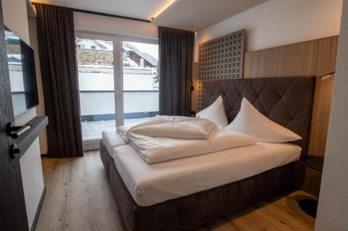 sypialnia z dużym łóżkiem z białą pościelą i poduszkami w obiekcie Place2be w mieście Ischgl