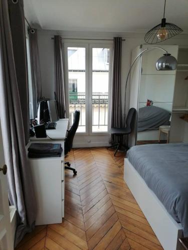 une chambre avec un lit et un bureau avec un ordinateur dans l'établissement Bel appartement Montparnasse 70m2, à Paris
