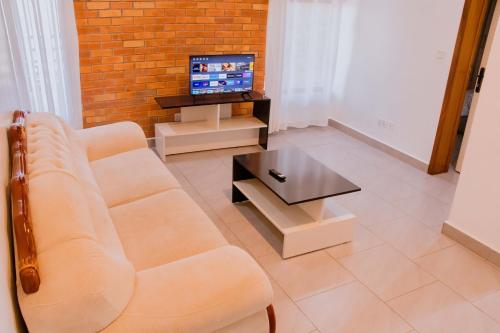 a living room with a couch and a tv at The Vacation Homes Apartments in Kigali