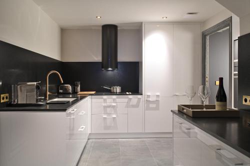 a kitchen with white cabinets and a black wall at Les 2 chalets - Les appartements du Strato in Courchevel