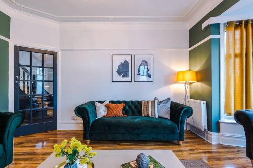 een woonkamer met een groene bank en een tafel bij Huge House in Leeds 6BR sleeps13 by PureStay Short Lets in Meanwood