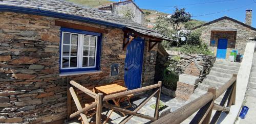 a stone cottage with a blue door and a table at Casa do Loureiro in Arganil