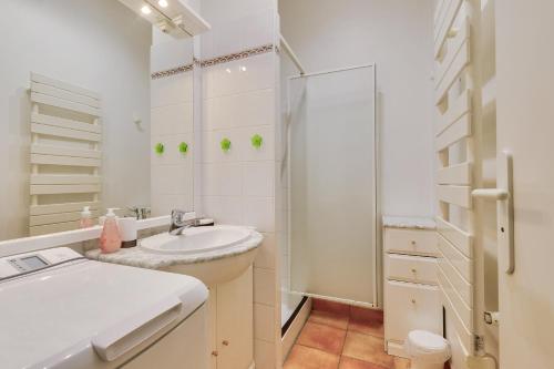 une salle de bain blanche avec un lavabo et une douche dans l'établissement 400m de la plage, appartement avec piscine, à Saint-Jean-de-Monts