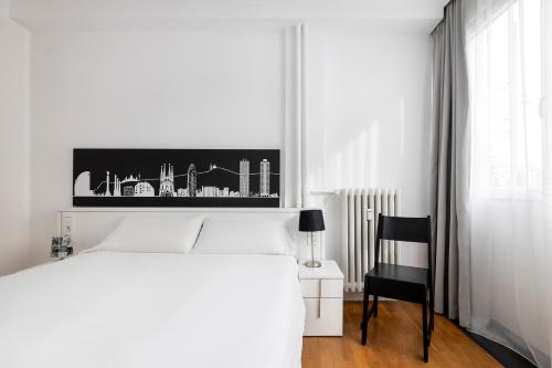 a bedroom with a white bed and a black chair at La Mejor Zona de Barcelona in Barcelona