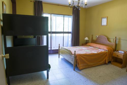 1 dormitorio con cama y ventana grande en La Casona del Pinar Albergue, en San Rafael