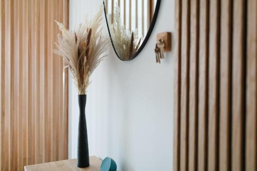 a mirror and a vase with feathers on a table at Haus Noena - Wohnung 7 Inselschatz in Norderney