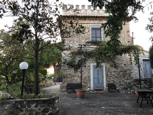 a stone building with a white door and a table and benches at Il Castello degli Ulivi-Agriturismo in natura in Roccella Ionica