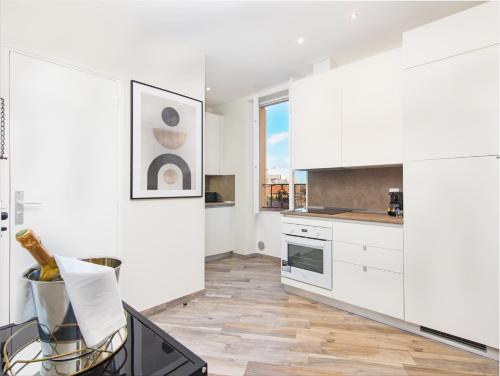 une cuisine avec des armoires blanches et un plancher en bois dans l'établissement 2mn Monaco - Hypercentre - Appartement rénové - BI, à Beausoleil