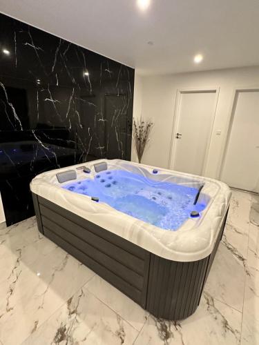 a jacuzzi tub in a bathroom with a black wall at Appartement cosy jacuzzi spa 70M2 in Châtenois