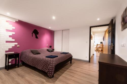 a bedroom with a purple accent wall and a bed at Appartement spa privatif et cinéma centre ville in Metz