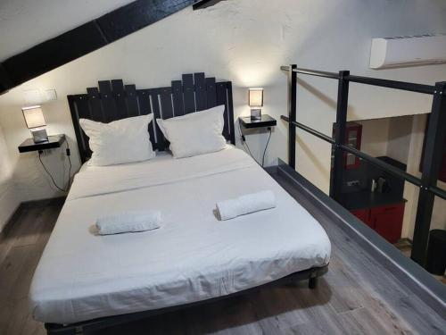 een slaapkamer met een groot wit bed met 2 kussens bij Loft idéalement placé Mer, Aéroport, Centre Ville in Nice