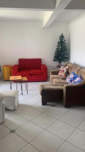 a living room with a red couch and a christmas tree at Casa com 4 quartos e piscina pra aproveitar in Tramandaí
