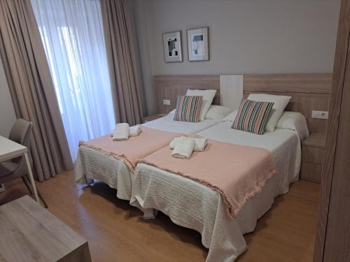 カルダス・デ・レイスにあるHotel Roquiñoのタオルが敷かれたベッドが2つある寝室