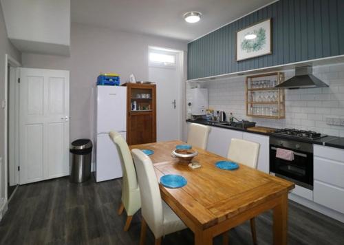 a kitchen with a wooden table with chairs and a refrigerator at The Regent Apartment 2 in Blackpool