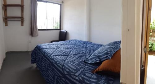 a bedroom with a bed with a blue comforter and a window at Domus Herbace in San Isidro de El General