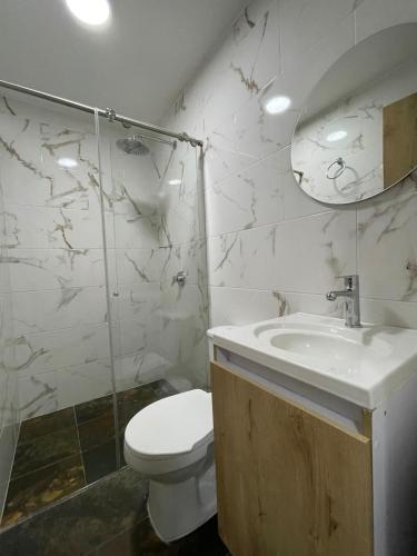 a white bathroom with a toilet and a sink at Hotel Boutique San Joaquin Plaza in Medellín