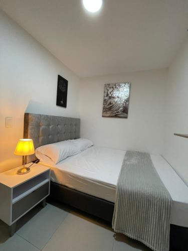 ein Schlafzimmer mit einem Bett und einem Nachttisch mit einer Lampe in der Unterkunft Hotel Boutique San Joaquin Plaza in Medellín