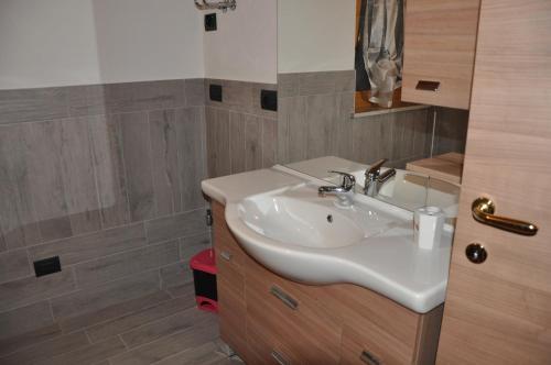 a bathroom with a white sink and a mirror at Le Foyer de la Ferme in Aosta