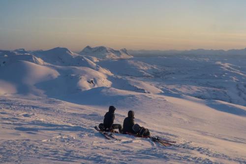 two people sitting on top of a snow covered mountain at Fjäll-lägenhet med fantastisk utsikt in Riksgränsen