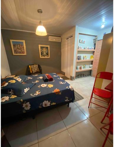 sypialnia z łóżkiem z niebieskim kocem i kwiatami w obiekcie Espaço privativo, funcional e aconchegante w mieście Santana do Livramento