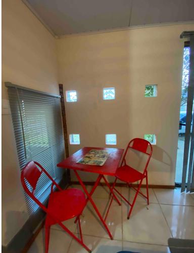 uma mesa vermelha e duas cadeiras num quarto em Espaço privativo, funcional e aconchegante em Santana do Livramento