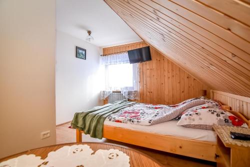 a bedroom with a bed with a wooden wall at U Capka in Poronin