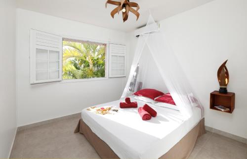 a bedroom with a bed with red pillows and a window at Villa Kanelle, F4, commerces et plage à 100m, in Le Diamant