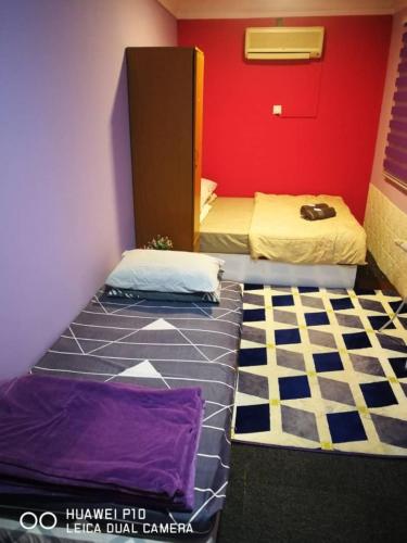 a room with two beds and a red wall at Homestay Teratak Tuan Muda in Air Molek