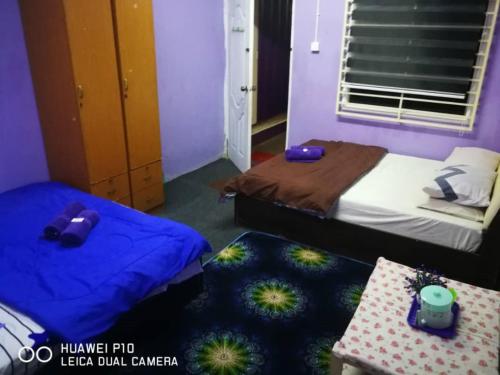 a room with two beds and a table in it at Homestay Teratak Tuan Muda in Air Molek