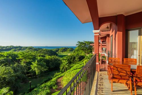 einen Balkon mit Stühlen und Blick auf einen Golfplatz in der Unterkunft Bougainvillea 2306 - Luxury Condo Reserva Conchal in Playa Conchal