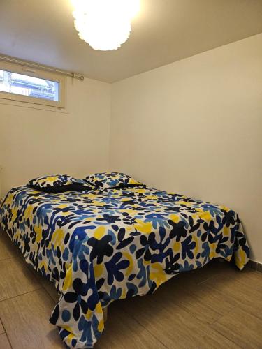 a bedroom with a bed with a blue and yellow comforter at Villa Hélène in Créteil