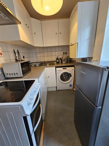 a kitchen with white cabinets and a black refrigerator at Camden Studio in London