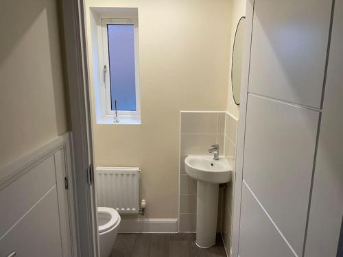 uma casa de banho com um lavatório, um WC e uma janela. em Beautiful Family Home em Mickleover