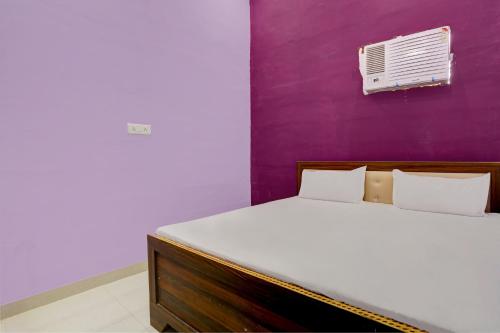 a bedroom with a bed and a purple wall at Hotel O Chaudhary Hotel in Tatārpur