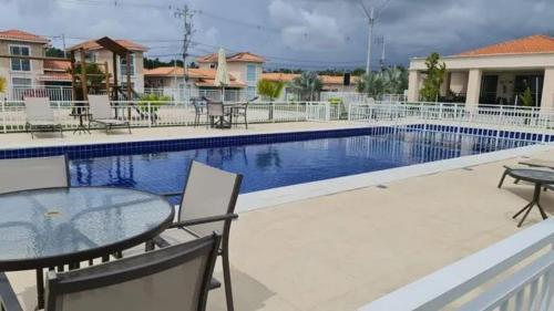 una piscina con tavolo e sedie accanto di Residencial Acácias Guarajuba a Camassari