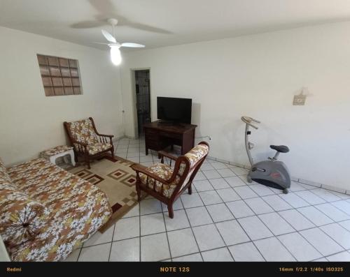 ein Wohnzimmer mit einem Bett und Stühlen sowie einem TV in der Unterkunft Casa PRAIA DOS INGLESES in Florianópolis