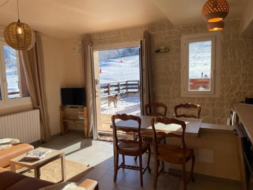 una sala de estar con una mesa y un perro mirando por la ventana en Le Logis de Bamby en Ancelle